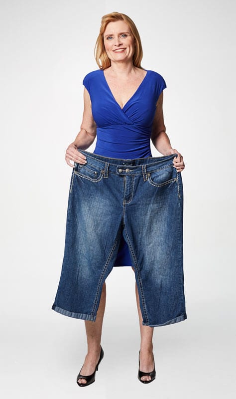Deborah holding up large jeans after losing weight on the SlimFast Plan