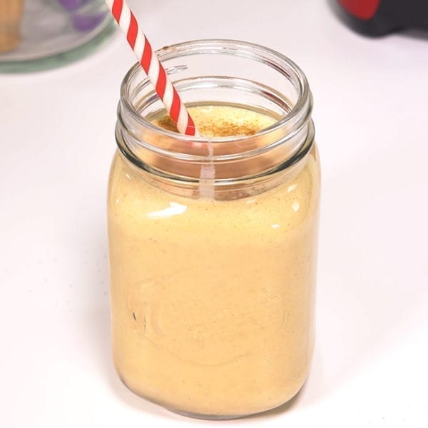 Power Pumpkin Smoothie in a mason jar with a red and white straw and topped with cinnamon.