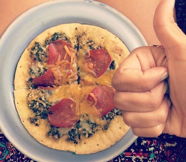 Personal pizza with pesto, cheese, and pepperoni.