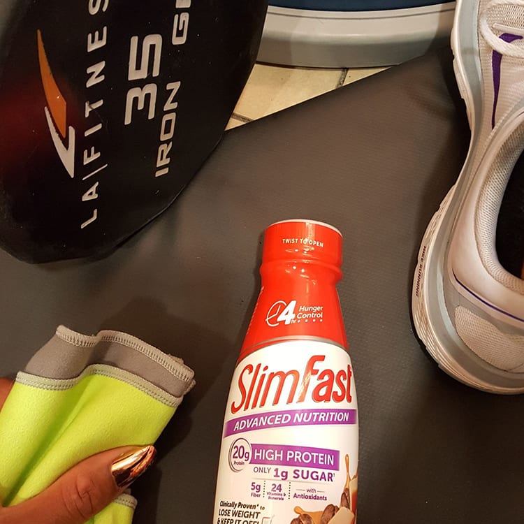 SlimFast ready to drink shake on a gym mat after a workout.