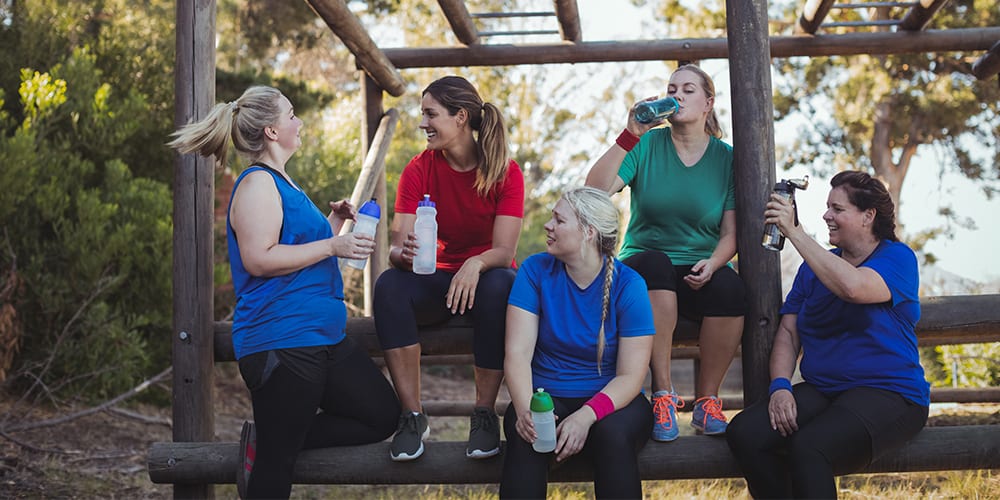 A group of women drinking water and talking after a workout.