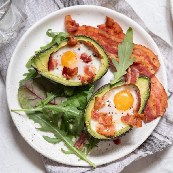 Plate of bacon slices and avocado filled with egg and bacon bits