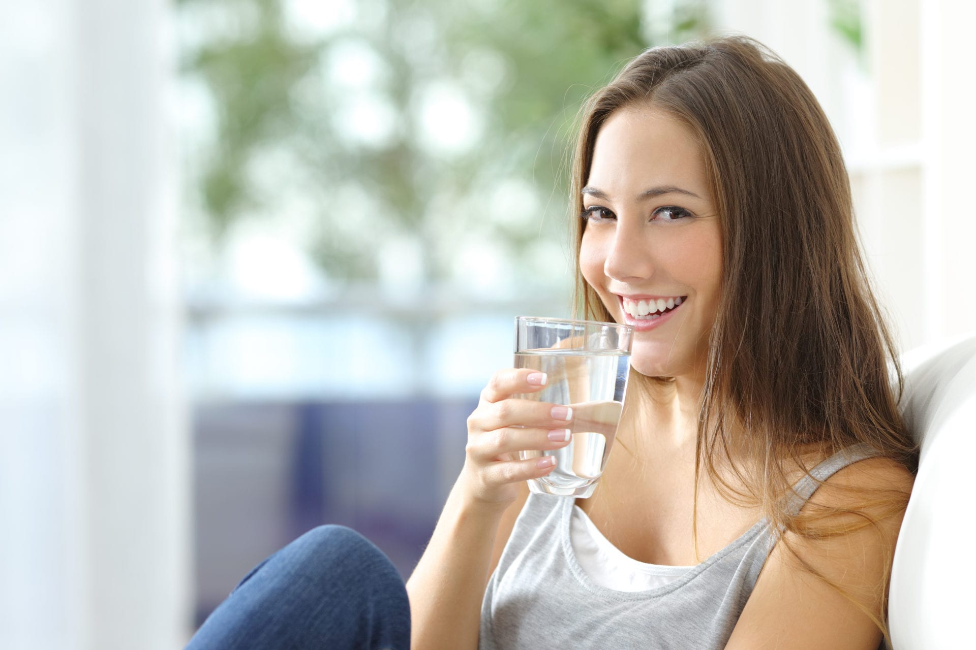 Woman sitting down and drinking a glass of water.
