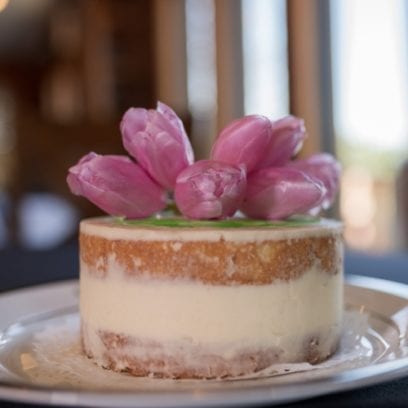 Vanilla Keto Wedding Cake with pink flowers on top.
